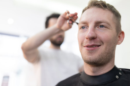 Man smiling receiving haircut by professional hairdresserの写真素材