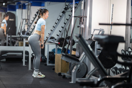 Woman exercising triceps using cable machine in gym