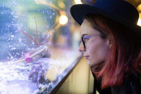 Woman observing live lobster in restaurant aquarium for dinnerの写真素材