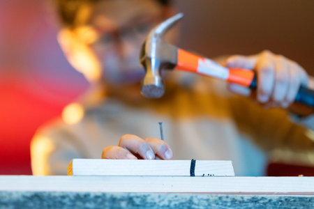 Person hammering nail into wood with tool