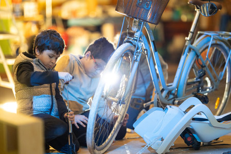 Boys learning skills repairing bicycle with air pumpの写真素材
