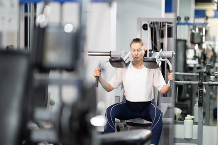 Woman training shoulder strength using gym equipment