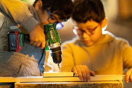 Children learning woodworking using cordless drill on woodの写真素材