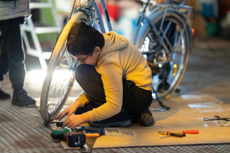 Young boy learning bicycle repair skills in workshopの写真素材