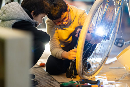 Boys learning bicycle repair using pumpの写真素材