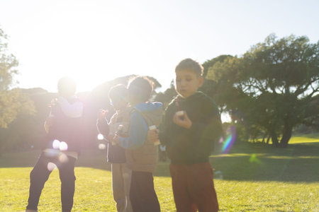 Children blowing soap bubbles in sunny park