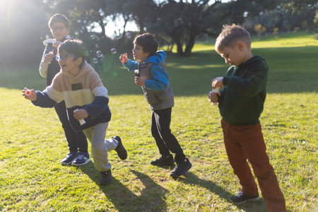 Group of boys running and blowing soap bubbles in parkの写真素材