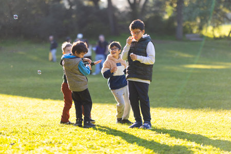 Group of boys having fun playing with bubbles outdoors