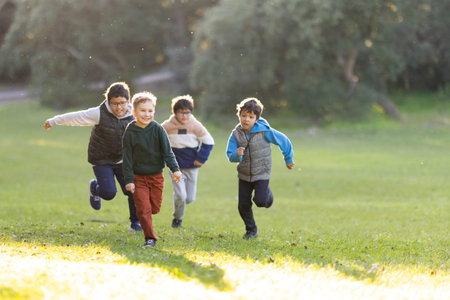 Diverse boys playing running together on green grassの写真素材