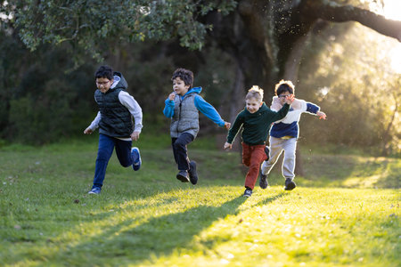Four smiling boys running happily outdoors enjoying childhoodの写真素材