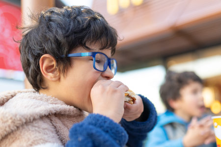 Young boy eating burger enjoying fast food mealの写真素材