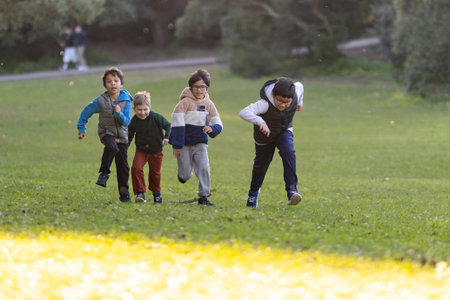 Four happy boys running and playing in park