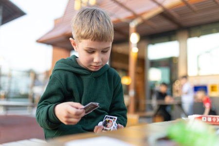 Young boy concentrating playing card game outdoors
