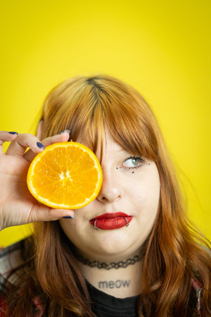 Young woman covering eye with orange sliceの写真素材