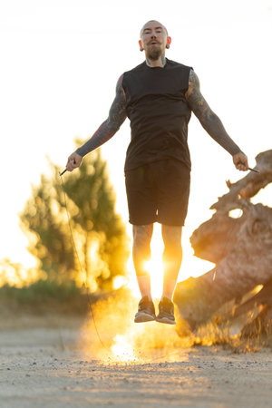 Man jumps while skipping rope during sunset in an outdoor setting