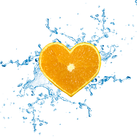 A heart shaped orange fruit with water splashes on a white background.の写真素材