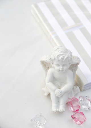 A little miniature statue of a white angel with wings on a white backgroundの写真素材