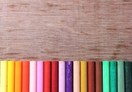 Crayons lined up in rainbow isolated on wood の写真素材