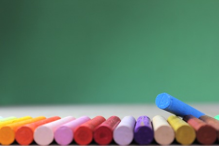 Crayons lined up in rainbow isolated on green の写真素材