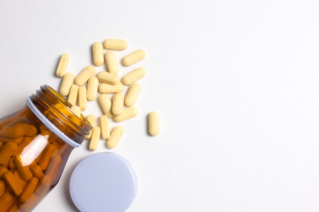 Prescription pill bottle spilling pills on to surface isolated on a white background の写真素材