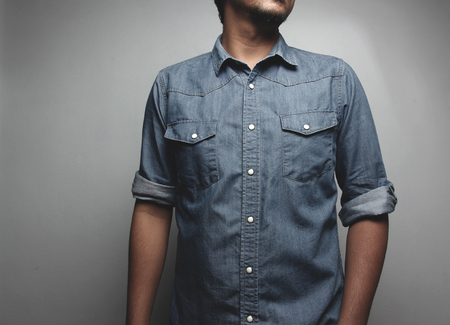 Close up Portrait of a  young man in a blue jeans shirt on the background of whiteの写真素材