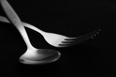 fork and spoon isolated on black backgroundの写真素材