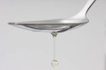 Close up syrup dripping from the spoon on white back groundの写真素材
