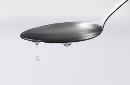 Close up syrup dripping from the spoon on white back groundの写真素材