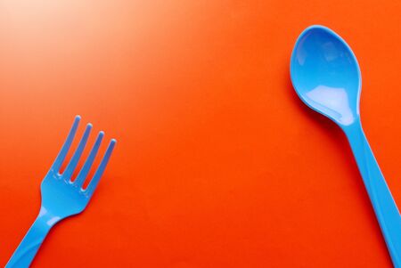 Colorful plastic spoon isolated on orange background.の写真素材