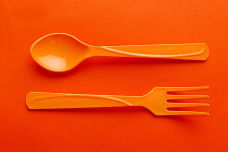 Colorful plastic spoon isolated on orange background.の写真素材