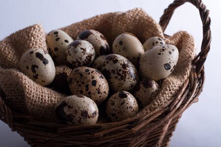 Easter quail eggs in a basket on a white backgroundの写真素材