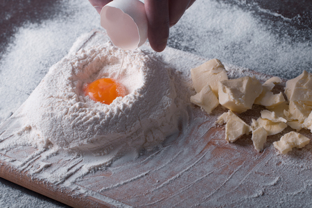 Douth, food, cooking concept - preparing douth - cooking progress and ingridients, Chef pours egg yolk from eggshell into flourの写真素材