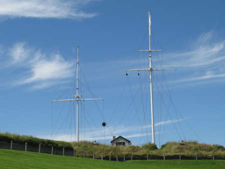 Two empty flagpoles standing on a green hill