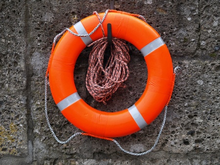 Orange lifebelt hanging on a concrete wall.