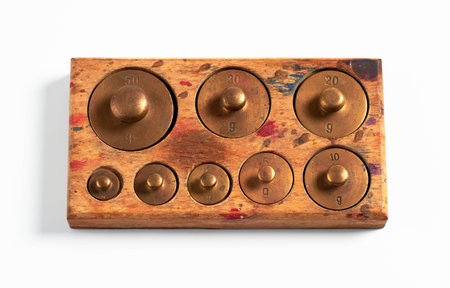 Old brass metric weights in a tray of woodの写真素材