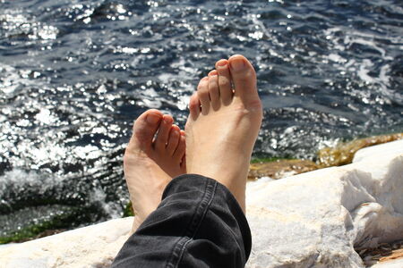 Bare feet facing the sea in a shinning day