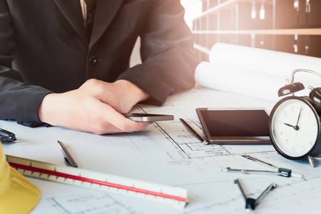 Business engineering holding and using a smartphone in office morning timeの写真素材