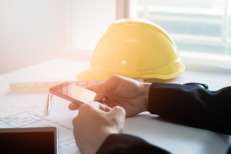 A business person holding and using a smartphone on the desk in an office.の写真素材