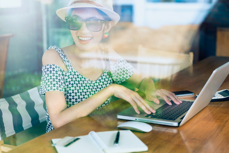 Young woman enjoying working sitting near window in the coffee shop with reflection of windowの写真素材