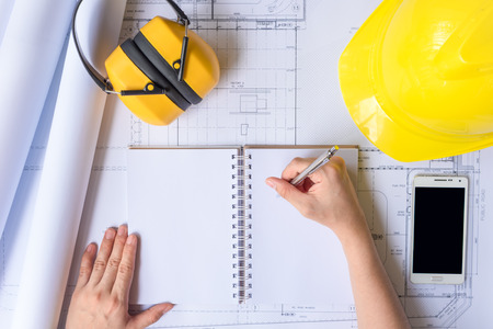 Engineer person working to building design concept with yellow helmet. Top view from above with copy...