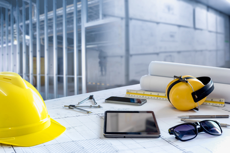 Desk of civil engineer., Working with blueprint and safety equipment against building construction.の写真素材