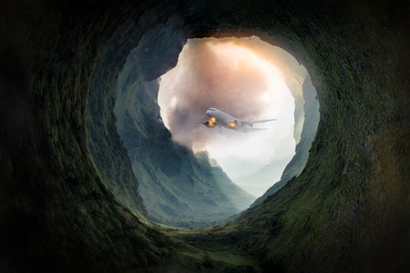 Dreams travel of airplane was flying through entrance to the cave in the green mountain., This extraordinary flight through a narrow cave on a rugged green mountainside in the forest.の写真素材