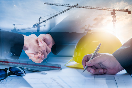 Double exposure of construction site and Business people shaking hands after the contract is signed...