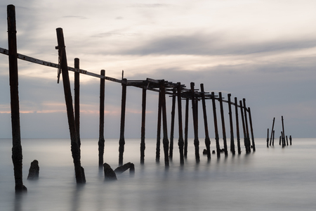 Old wooden bridge wreck on beach after storm affectの写真素材