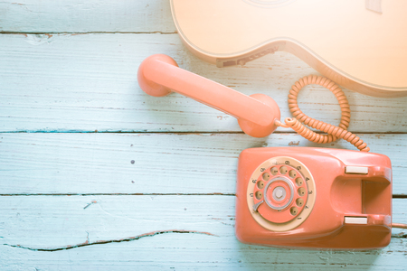 Retro orange-red telephone and the guitar on the old wooden table with copy space for text or your subject in the pastの写真素材