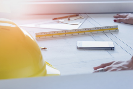 Desk of engineer designer and architect in the office with equipment and drawing paper for working plan on evening timeの写真素材
