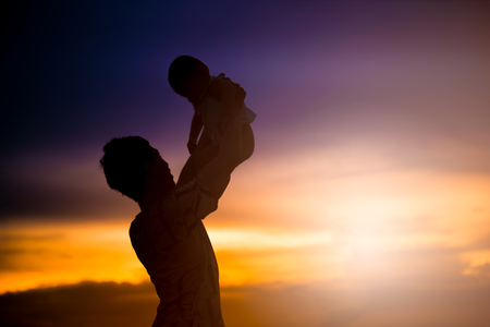 Father holds his child with love. silhouette on the sunset timeの写真素材