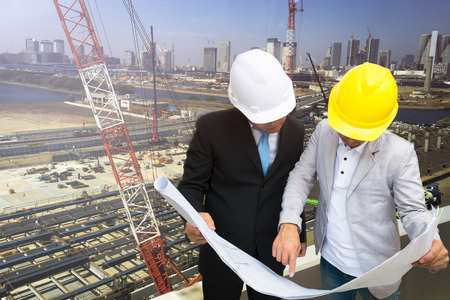 Management consulting with engineers working and holding blueprint engineer designer with helmet...