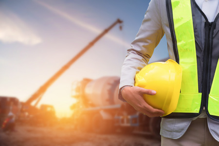 Engineer or Safety officer holding hard hat with the mobile crane machine is background in...