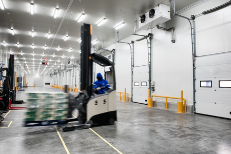 Worker Stand-on stacker truck used to lift and move the ready meals goods stock in cold room or freezer room.の写真素材